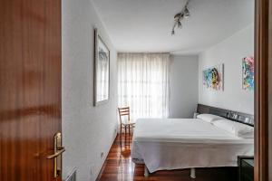 1 dormitorio con cama blanca y ventana en Piso con Piscina, en Santander