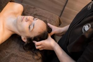 a woman laying on a couch cutting her hair at Le Logis des Prés Verts Villa avec Jacuzzi Privatif in Jouey