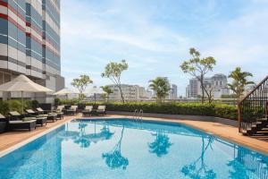 einen Pool mit Stühlen und ein Gebäude in der Unterkunft Melia Hanoi in Hanoi