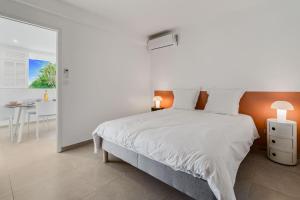 a white bedroom with a large bed and a table at Villa Alexina in Le Robert +31 photos