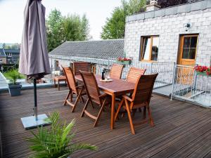 una mesa de madera y sillas en una terraza con sombrilla en Gite les bons amis, en Plombières