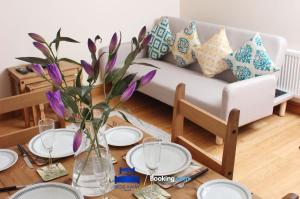 a living room with a couch and a table with purple flowers at Four Bedroom House By Beds Away Short Lets & Serviced Accommodation Oxford With Free Parking & Garden Access in Oxford
