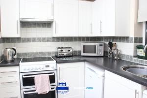 a kitchen with white cabinets and a stove top oven at Four Bedroom House By Beds Away Short Lets & Serviced Accommodation Oxford With Free Parking & Garden Access in Oxford