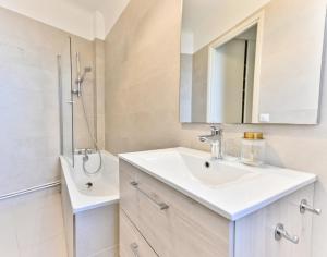 biała łazienka z umywalką i prysznicem w obiekcie Apparement à 5 minutes de Paris - Neuilly w mieście Neuilly-sur-Seine