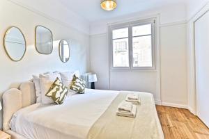 een witte slaapkamer met een groot bed met spiegels aan de muur bij Apparement à 5 minutes de Paris - Neuilly in Neuilly-sur-Seine