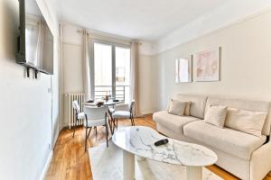 een woonkamer met een bank en een tafel bij Apparement à 5 minutes de Paris - Neuilly in Neuilly-sur-Seine