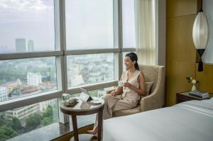 a woman sitting in a chair in a room with a cup of coffee at Melia Hanoi in Hanoi