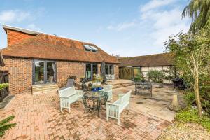a brick patio with white chairs and a table at Spacious & Stylish Home Nr Chichester in Fishbourne