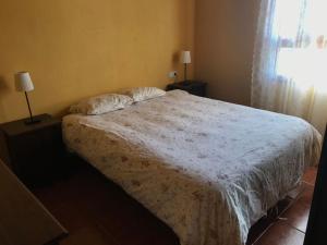 1 dormitorio con 1 cama con edredón blanco y ventana en Una casa con vistas en La Caleta