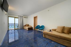 a living room with a couch and two blue chairs at Ninos Grand Beach Resort in Kastrosikia