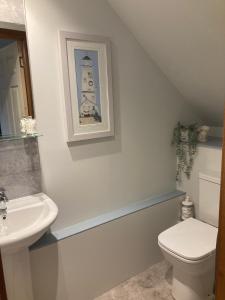 a bathroom with a sink toilet and a picture of a lighthouse at Kirkside in Auchterarder