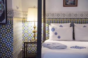 łóżko z białymi poduszkami i lampą obok w obiekcie Ryad El Borj w Marakeszu