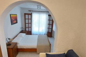a bedroom with a bed and an arched window at Esperides Villa in Sani Beach