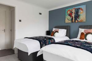 2 łóżka w pokoju z niebieskimi ścianami i obrazem słonia w obiekcie Evergreen Cottage Orsett w mieście Orsett