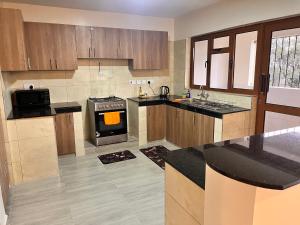 a kitchen with wooden cabinets and a stove top oven at Nakuru Town Suites With Heated Pool, GYM, Secure Parking in Nakuru