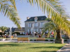 a building with a palm tree and benches in front at Domaine Les Jardins dArsene in Tinténiac