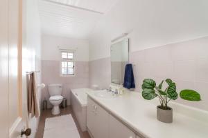 Baño blanco con lavabo y aseo en Escape to Paradise in Plett - Back up Electricity, en Plettenberg Bay