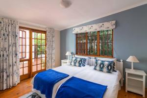 a bedroom with a blue and white bed and windows at Escape to Paradise in Plett - Back up Electricity in Plettenberg Bay