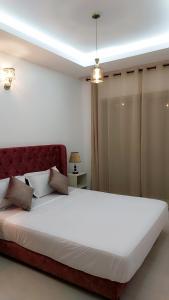 Appartement Perla - Costa Bouznika في بوزنيقة: سرير أبيض كبير مع اللوح الأمامي الأحمر في غرفة النوم
