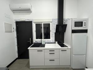 a white kitchen with a sink and a microwave at Cotrades 2 San Blas-canillejas in Madrid