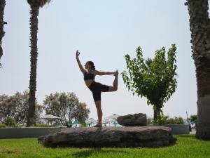 ファリラキにあるEsperos Palace Resort & Spaの岩の上でヨガ姿勢をしている女性