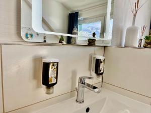 um lavatório de casa de banho com 2 dispensadores de sabão e um espelho em Almsternderl 2.0 - gemütliches Appartment in Gosau em Gosau