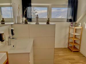 a white bathroom with a sink and two windows at Almsternderl 2.0 - gemütliches Appartment in Gosau in Gosau