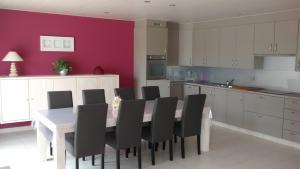 a kitchen with a white table and black chairs at De Lekkermond in Diksmuide