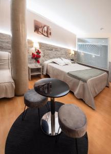 een slaapkamer met een bed, een tafel en 2 krukken bij Hotel Palau de Girona in Sant Julià De Ramis