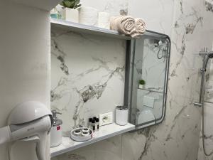 a bathroom with a mirror on a marble wall at Romeo apt with private garden in Korçë +29 photos