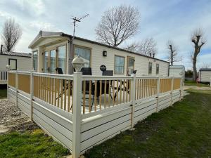 Casa blanca con porche y valla en New Beach Holiday Park, en Kent