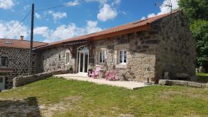 a stone house with two pink chairs in front of it at " gite Au Pied Du Chapelas" in Le Plagnal