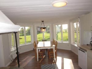 a dining room with a table and chairs and windows at Huldas gård villa med självhushåll in Kumla