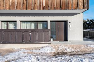 ein Haus mit braunen Türen im Schnee in der Unterkunft Mountain Meadows Apt 1 in Olang