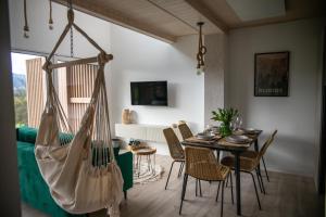 sala de estar con mesa, sillas y hamaca en Beskid Sielski - klimatyczne domki w Lipowej z widokiem na góry i sauną - Dream Apart en Żywiec