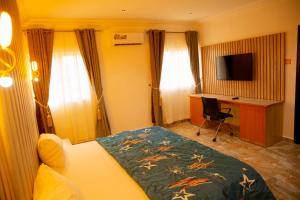 een slaapkamer met een bed, een bureau en een televisie bij Cogent Apartments Single Rooms in Uyo