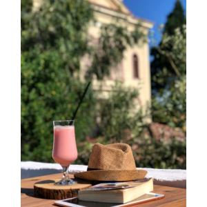 a straw hat and a glass of pink drink on a table at La Luna Otel Cunda in Ayvalık