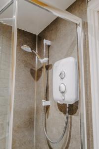 y baño con ducha y dispensador de jabón blanco. en Goodwin House en Keswick
