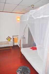 a bedroom with a bed with a mosquito net at Sea Breeze Inn Talalla in Talalla
