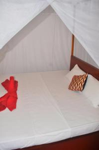 a white bed with a red bow on it at Sea Breeze Inn Talalla in Talalla