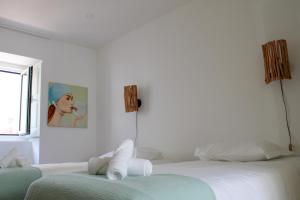 1 dormitorio blanco con 2 camas y una pintura en la pared en Casa dos Cucos, en Ericeira