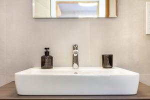 Un lavabo de baño con dispensador de jabón y un espejo. en Mountain Meadows Apt 2, en Valdaora 11 fotos más