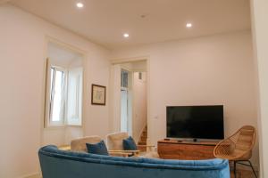 sala de estar con sofá azul y TV en Casa dos Cucos, en Ericeira