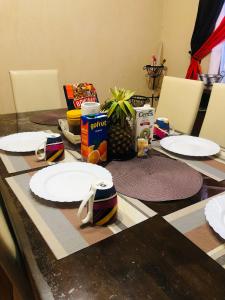 uma mesa com pratos brancos e uma mesa com cadeiras em weekend getaway fully furnished em Kiserian