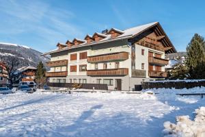 a large building with snow in front of it at Mountain Meadows Apt 3 in Valdaora