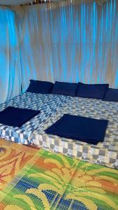 Una cama en una tienda con almohadas azules. en Lotus Jewel Forest Camping, en Sultan Bathery