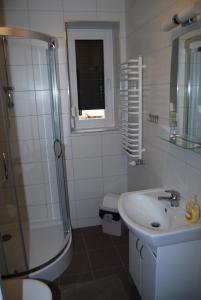 a white bathroom with a sink and a shower at Domek nad Muszynką in Muszyna