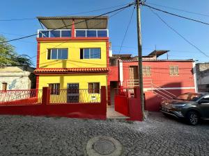 una casa amarilla frente a un edificio rojo en Cidade Velha - Cathedral view - 1Bdr Apart - 1 en Cidade Velha