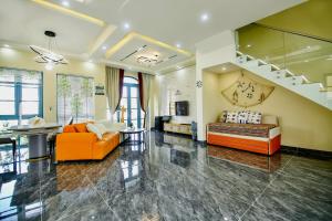 a living room with orange furniture and a staircase at Villa NovaWorld Phan Thiết - Bình Thuận in Phan Thiet
