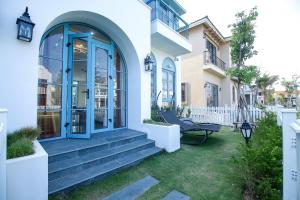 a white house with a blue door and stairs at Villa NovaWorld Phan Thiết - Bình Thuận in Phan Thiet